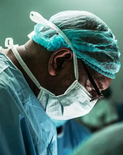 Surgeon in surgical scrubs and a mask, focused on performing surgery